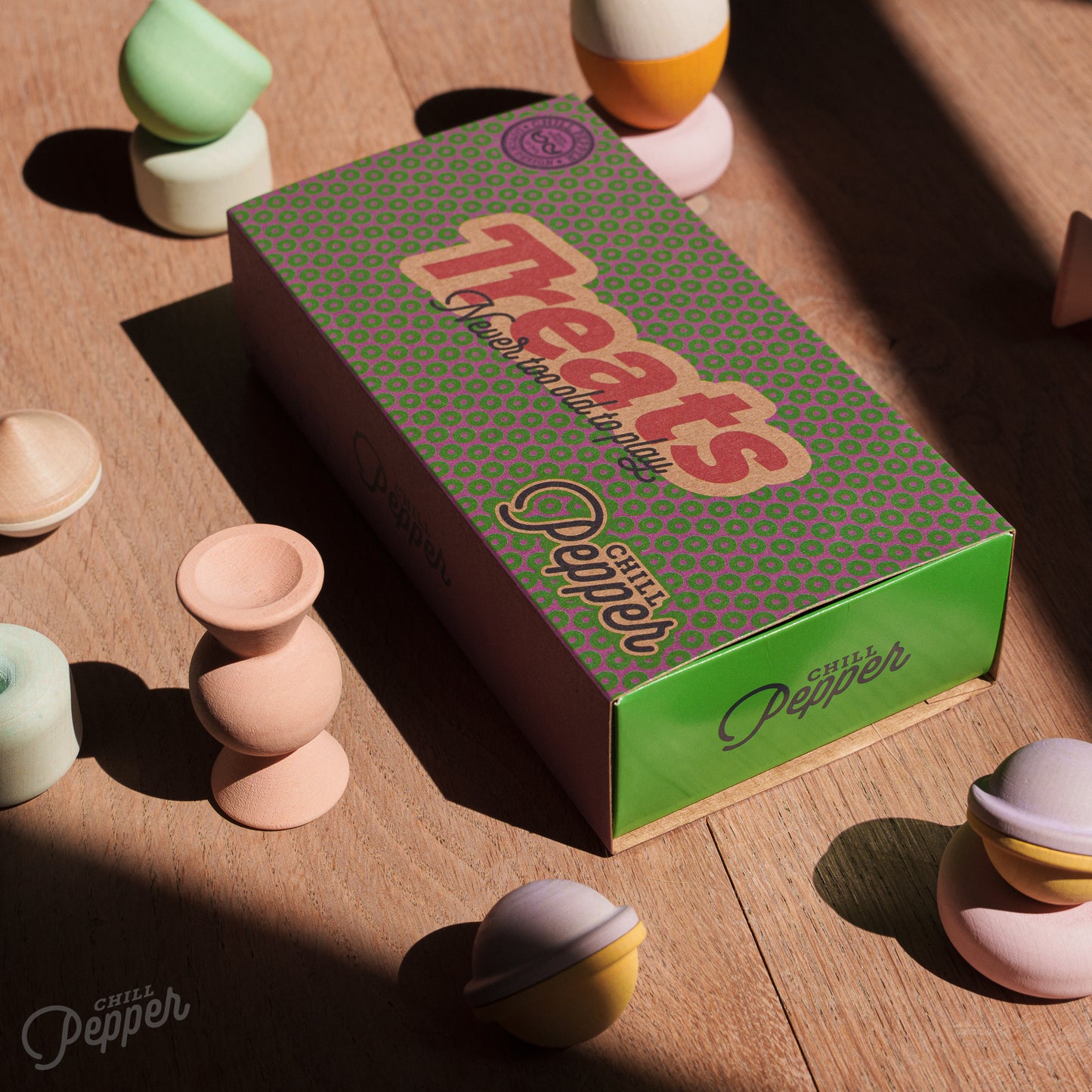Wooden Chill Pepper Treats stacking and spinning game for ages 3 and up, made from eco-friendly maple wood and non-toxic, water-based paints. The set includes a variety of pastel-colored candy-shaped pieces and a unique Magic Egg for open-ended play.