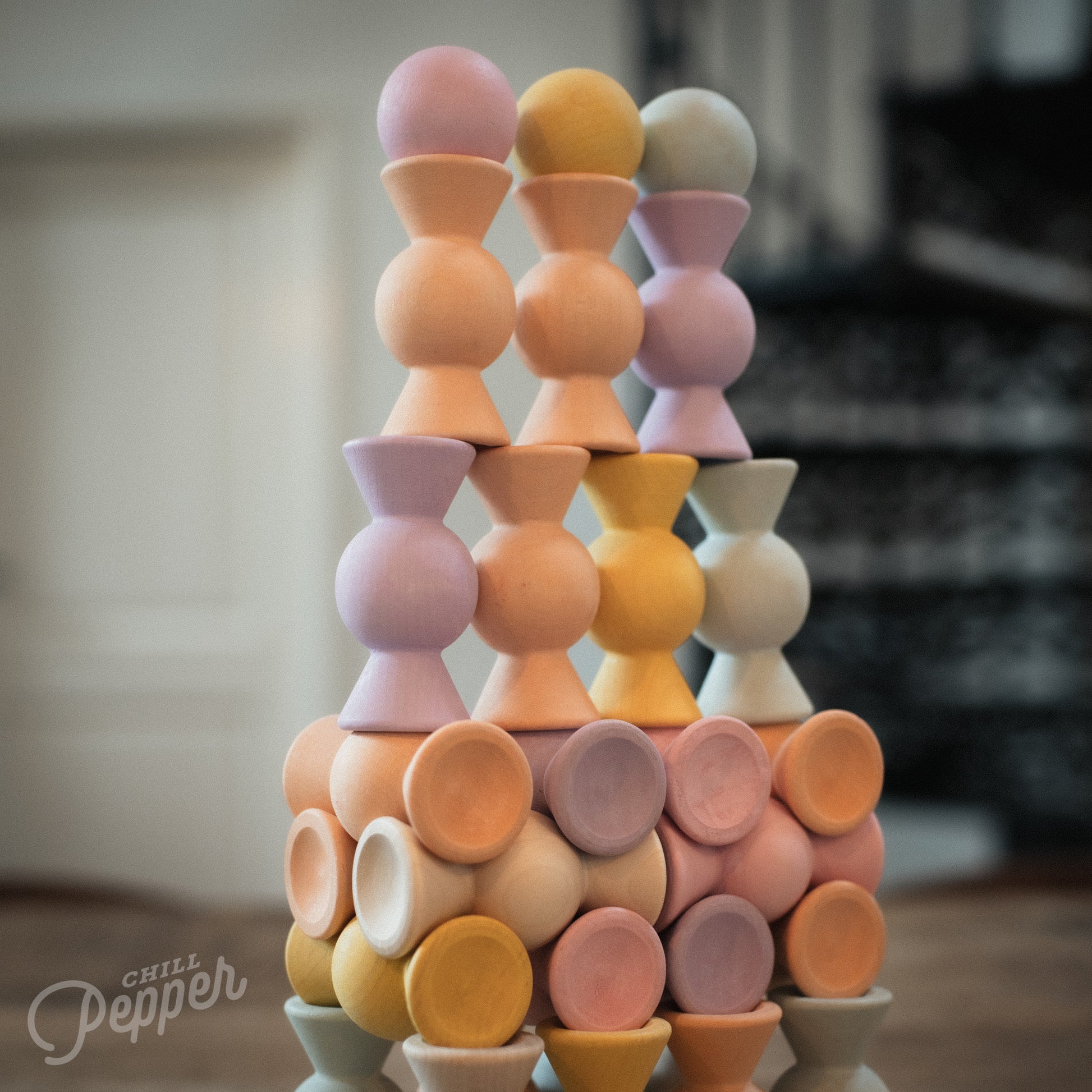 Wooden Chill Pepper Sweets stacking and spinning game for ages 3 and up, made from eco-friendly maple wood and non-toxic, water-based paints. The set includes 27 pastel-colored candy-shaped pieces and 6 gumballs for open-ended play.