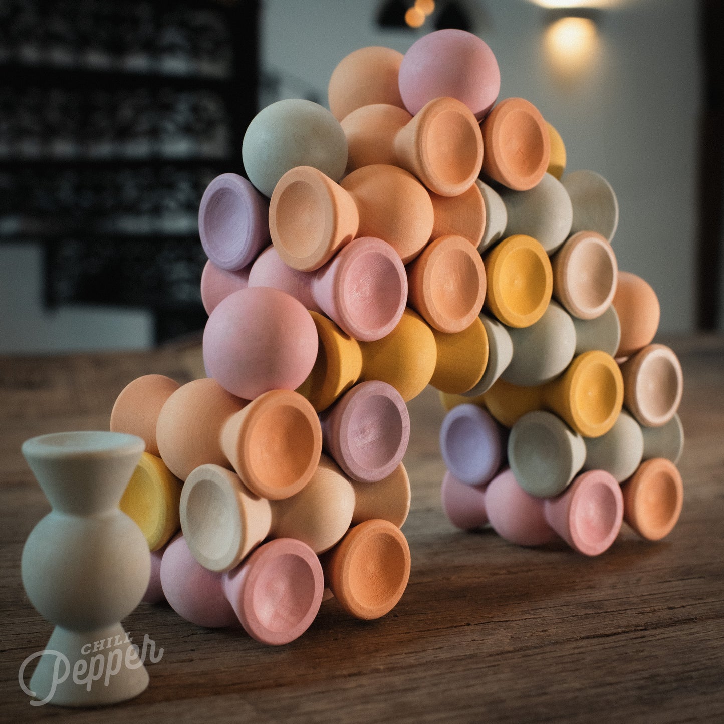 Wooden Chill Pepper Sweets stacking and spinning game for ages 3 and up, made from eco-friendly maple wood and non-toxic, water-based paints. The set includes 27 pastel-colored candy-shaped pieces and 6 gumballs for open-ended play.