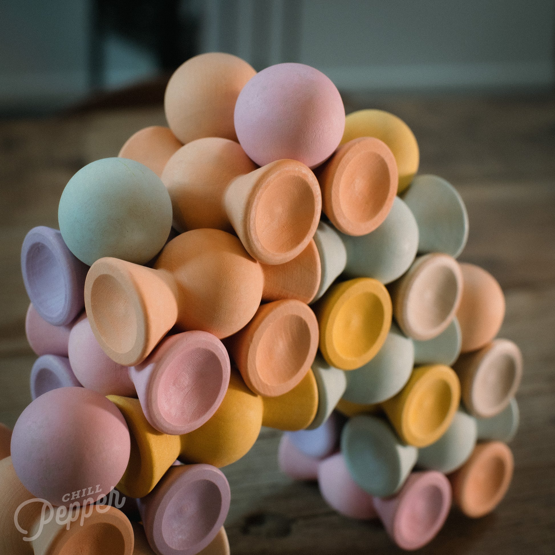 Wooden Chill Pepper Sweets stacking and spinning game for ages 3 and up, made from eco-friendly maple wood and non-toxic, water-based paints. The set includes 27 pastel-colored candy-shaped pieces and 6 gumballs for open-ended play.
