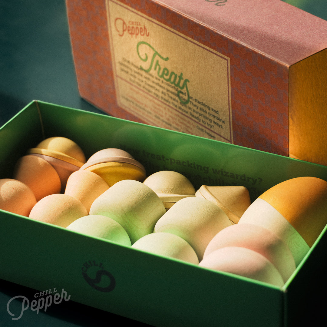 Wooden Chill Pepper Treats stacking and spinning game for ages 3 and up, made from eco-friendly maple wood and non-toxic, water-based paints. The set includes a variety of pastel-colored candy-shaped pieces and a unique Magic Egg for open-ended play.