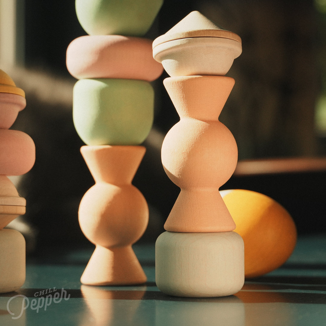 Wooden Chill Pepper Treats stacking and spinning game for ages 3 and up, made from eco-friendly maple wood and non-toxic, water-based paints. The set includes a variety of pastel-colored candy-shaped pieces and a unique Magic Egg for open-ended play.