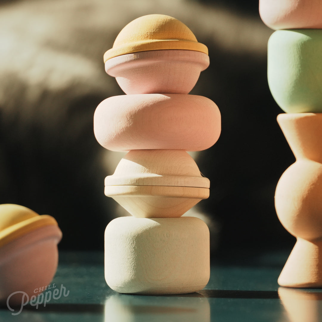 Wooden Chill Pepper Treats stacking and spinning game for ages 3 and up, made from eco-friendly maple wood and non-toxic, water-based paints. The set includes a variety of pastel-colored candy-shaped pieces and a unique Magic Egg for open-ended play.