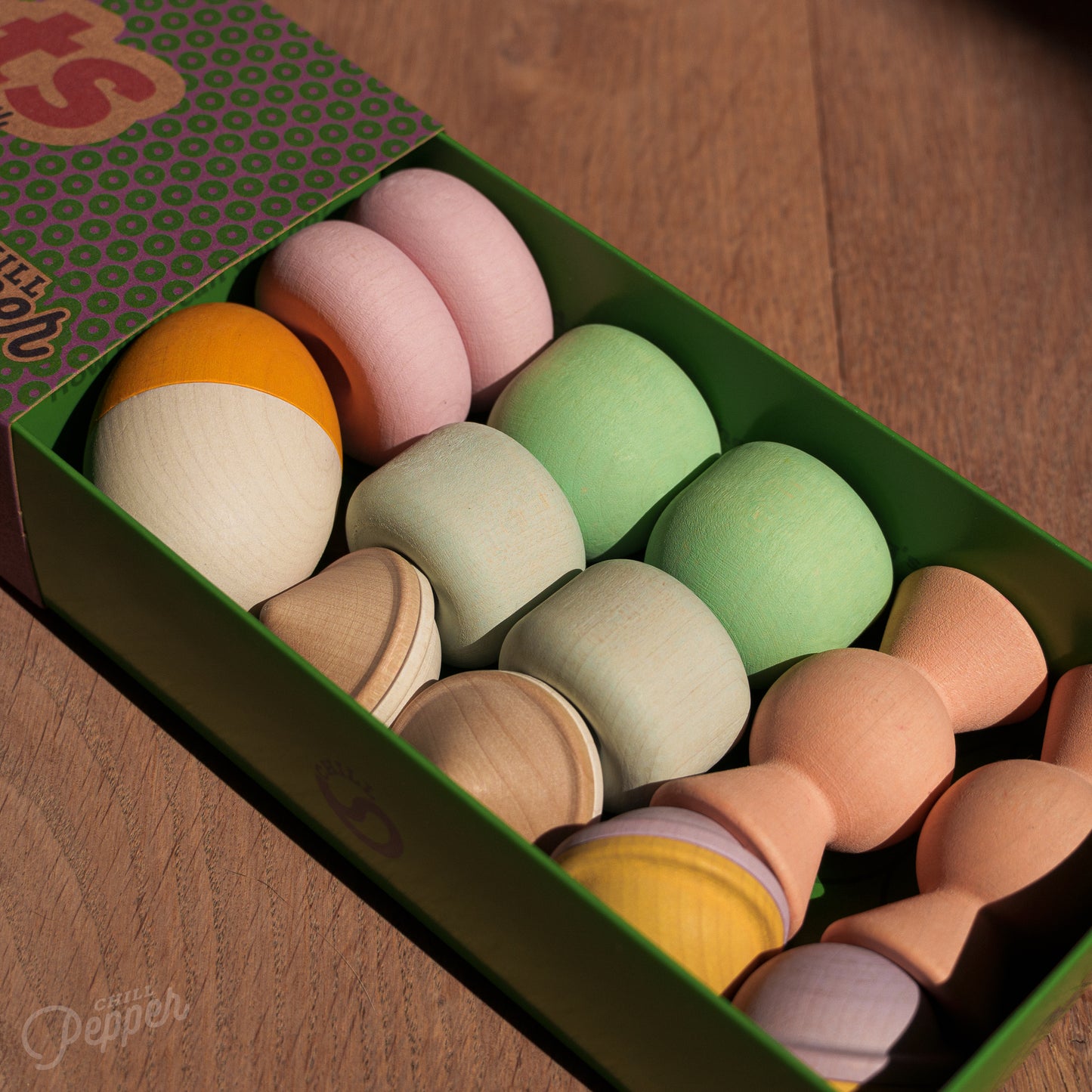Wooden Chill Pepper Treats stacking and spinning game for ages 3 and up, made from eco-friendly maple wood and non-toxic, water-based paints. The set includes a variety of pastel-colored candy-shaped pieces and a unique Magic Egg for open-ended play.