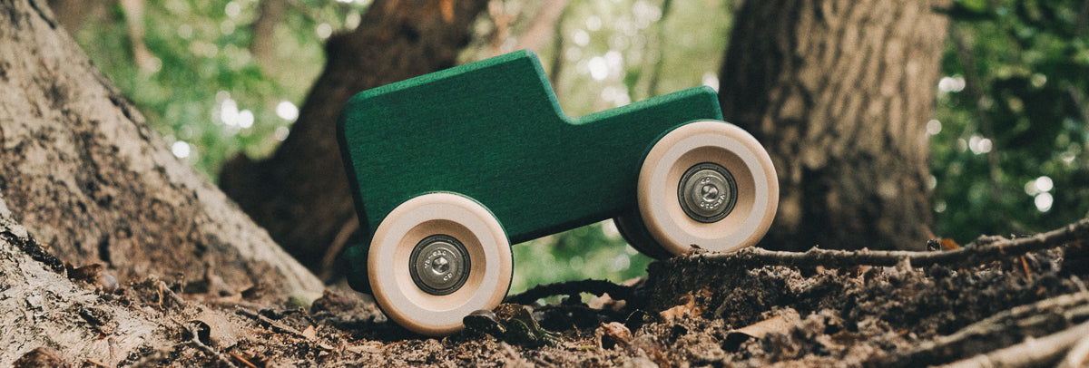 Chill pepper Chunkies wooden all-terrain wooden toy car in a forest.