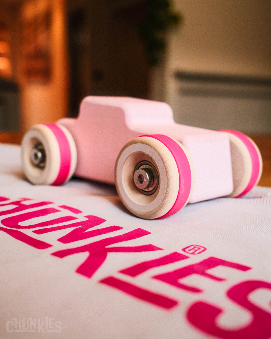 A Chill Pepper Chunkies No04  Wooden Toy Car The Hot Rod Perfectly Pink on a Chunkies branded shirt. All colors in this image are bright and pink. 