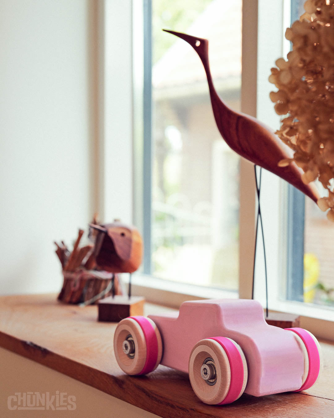 Chill Pepper Chunkies No04  Wooden Toy Car The Hot Rod Perfectly Pink in a window sill with wooden decorations. This big little car is ready for any adventure. Open for imaginative play.
