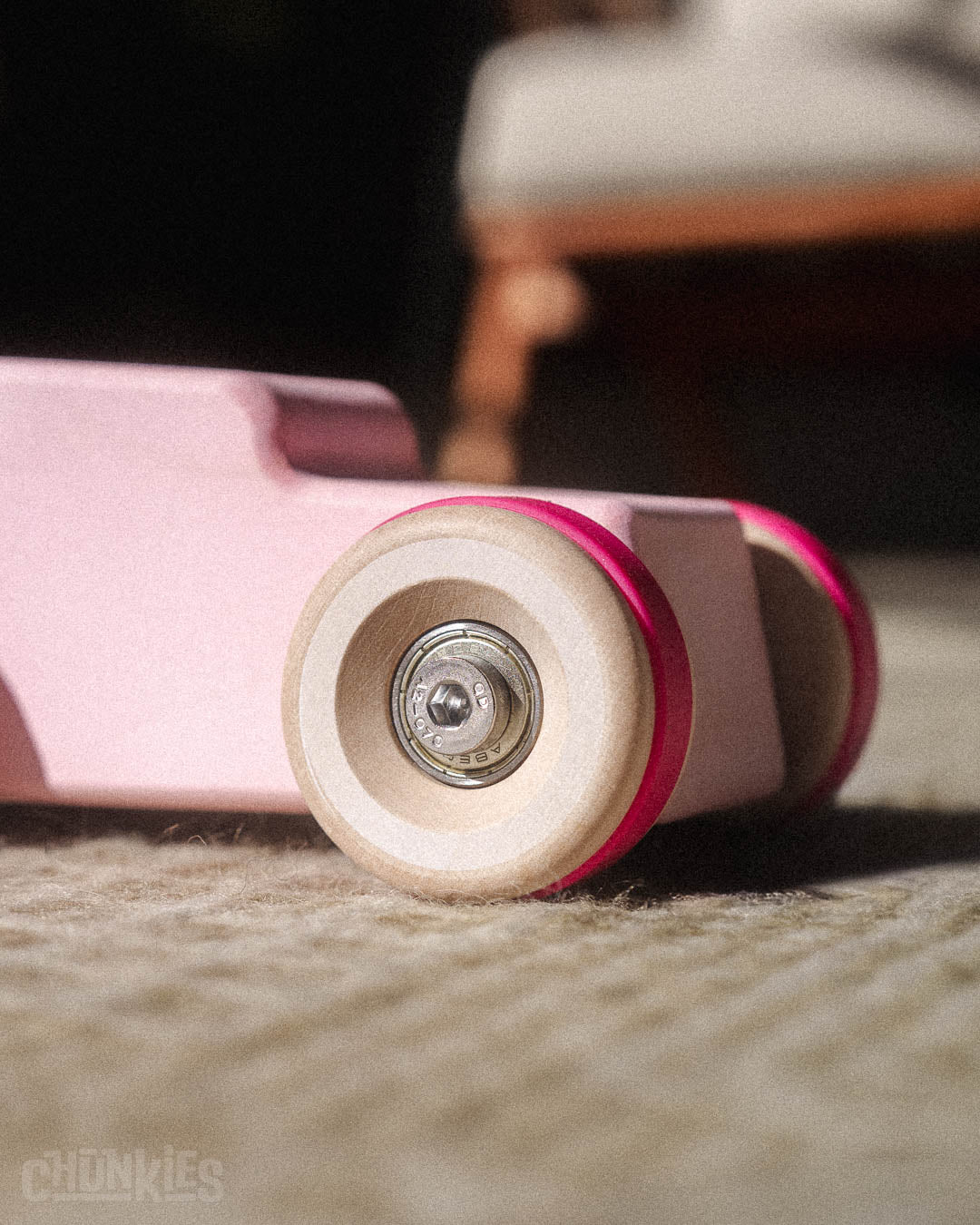 Close-up of the oversized solid wooden wheels and pro hardware on the Chill Pepper Chunkies No04  Wooden Toy Car The Hot Rod Perfectly Pink 