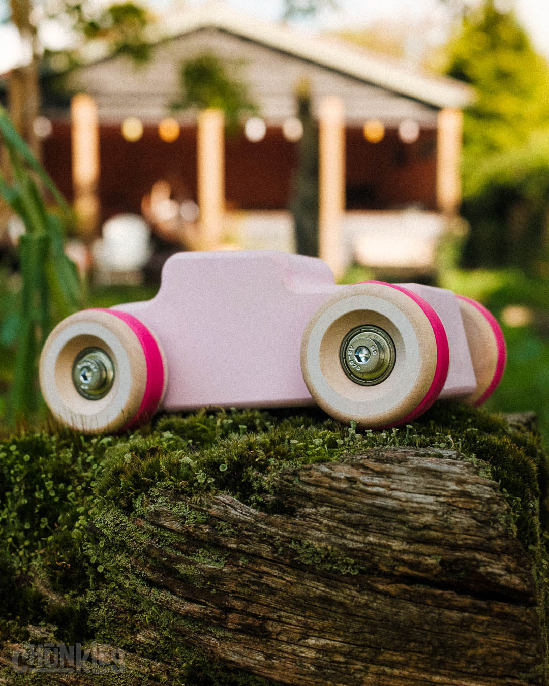 Outdoor shot of the Chill Pepper Chunkies No04  Wooden Toy Car The Hot Rod Perfectly Pink with a big wooden porch in the background