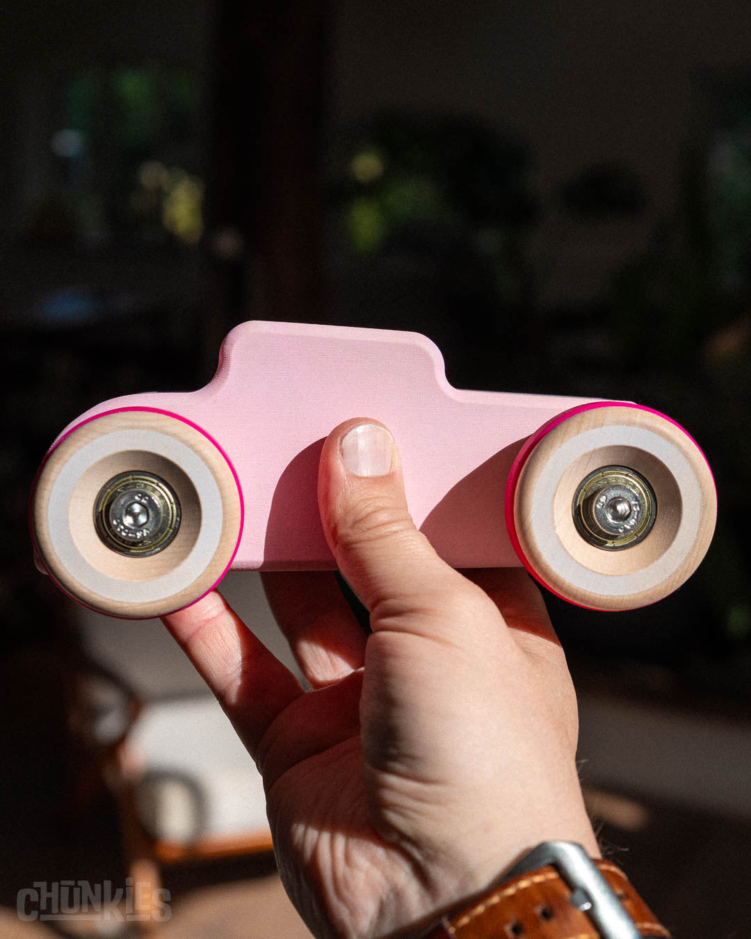 Hand held Chill Pepper Chunkies No04  Wooden Toy Car The Hot Rod Perfectly Pink to show scale. These solid wooden toy cars are much bigger than usual and due to the solid build with stainless steel heavy duty hardware and real skate bearings for a smooth ride these cars cars ride like no other. Made in Europe