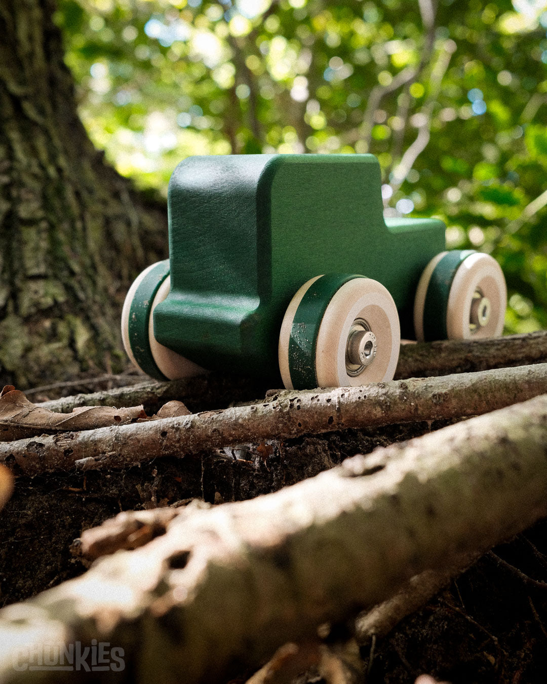 The big wheels of the Chunkies The explorer all-terrain wooden toy car easily conquers some wooden logs in a forest. Made in Germany