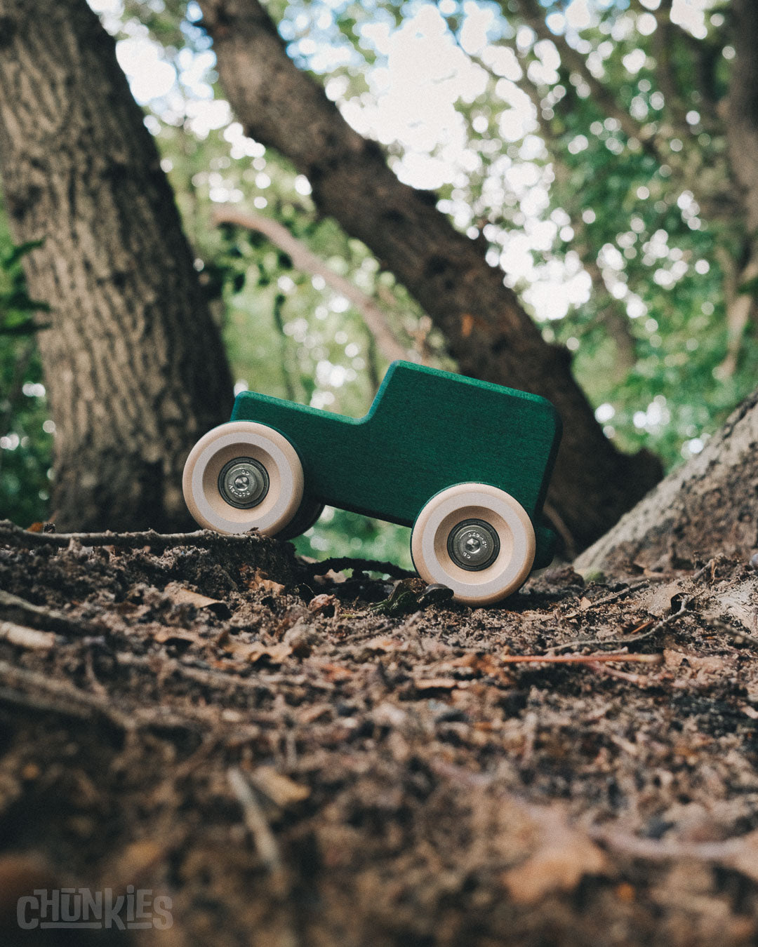 A vintage side shot of the Chill Pepper Chunkies No05 Wooden Toy Car The Explorer All-Terrain in a forest.