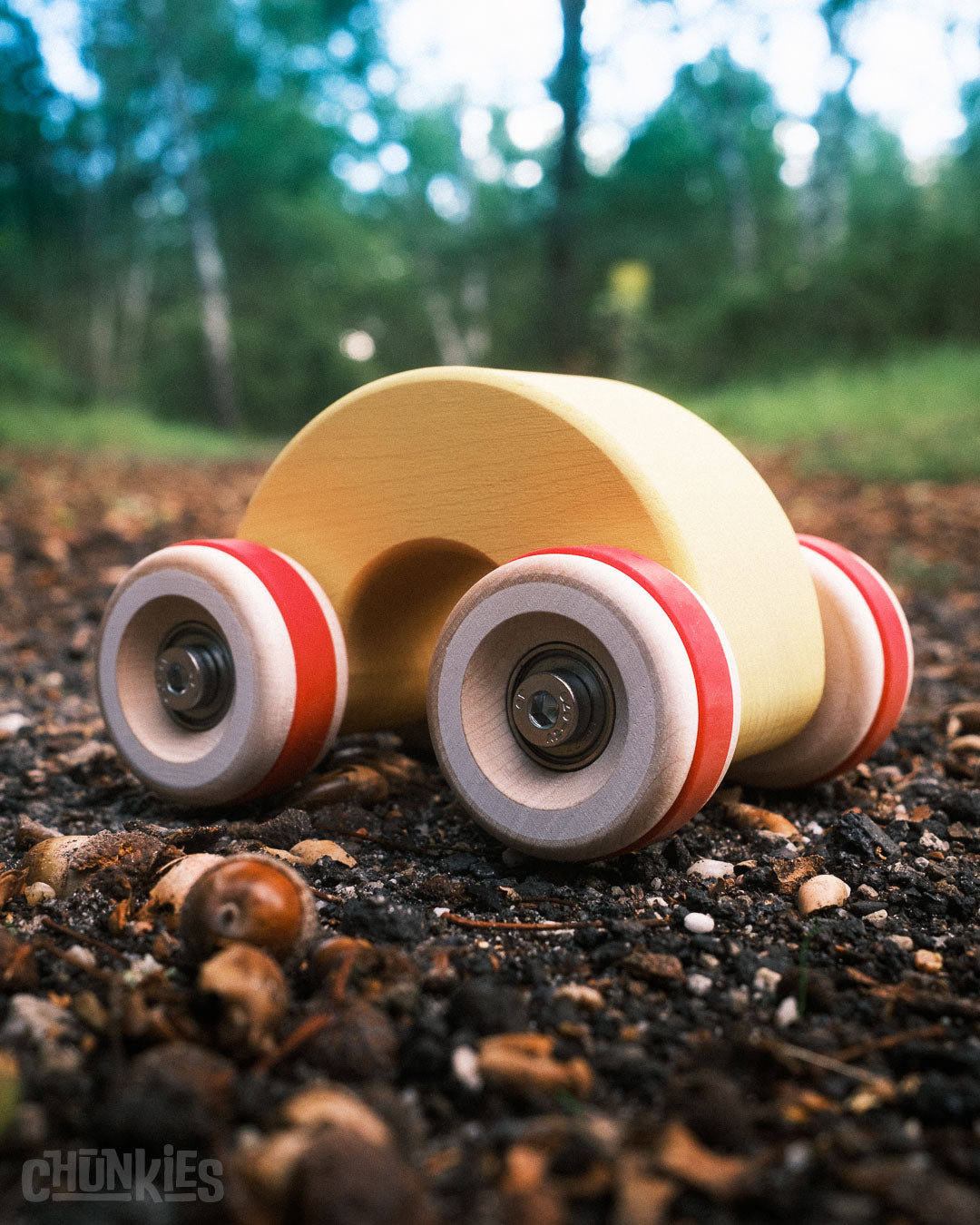 Forest shot of the Chill Pepper Chunkies No06 Wooden Toy Car The Rainbow. Trees in the background to show its heritage: European well maintained forest 