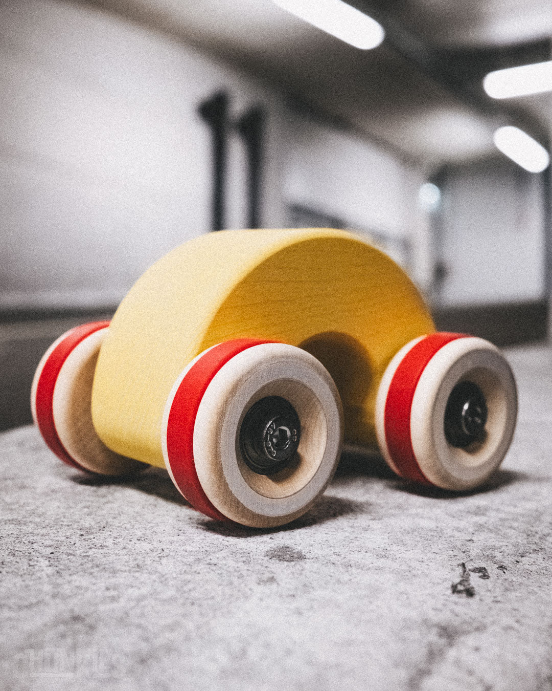 Chill Pepper Chunkies No06 Wooden Toy Car The Rainbow in a parking garage. A solid wooden sustainable toy car in the shape of a rainbow. The Yummy Yellow color is water based and child friendly. Made in Europe