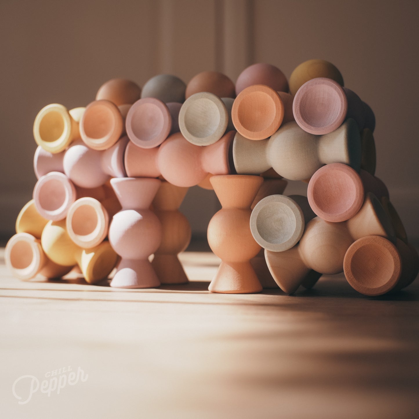 Wooden Chill Pepper Sweets stacking and spinning game for ages 3 and up, made from eco-friendly maple wood and non-toxic, water-based paints. The set includes 27 pastel-colored candy-shaped pieces and 6 gumballs for open-ended play.