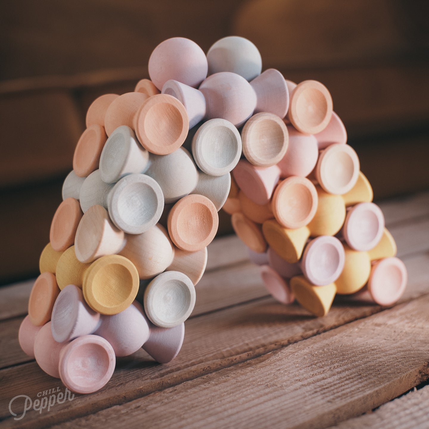 Chill Pepper Sweets wooden stacking game in the shape of candy. Stacked  in two interlocking piles facing each other and connecting at the top with some of the Gumballs on top. Sustainable, loose parts and open ended play