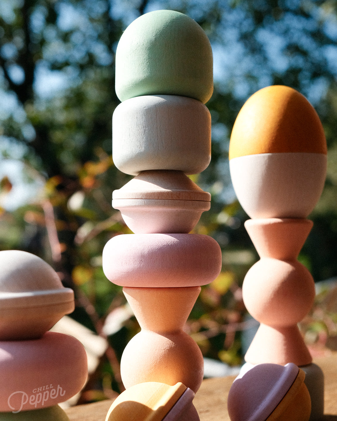 A close-up of Chill Pepper Treats – Wooden Stacking & Spinning Game. You can clearly see the wood grain and the pastel and soft texture of the child friendly finish