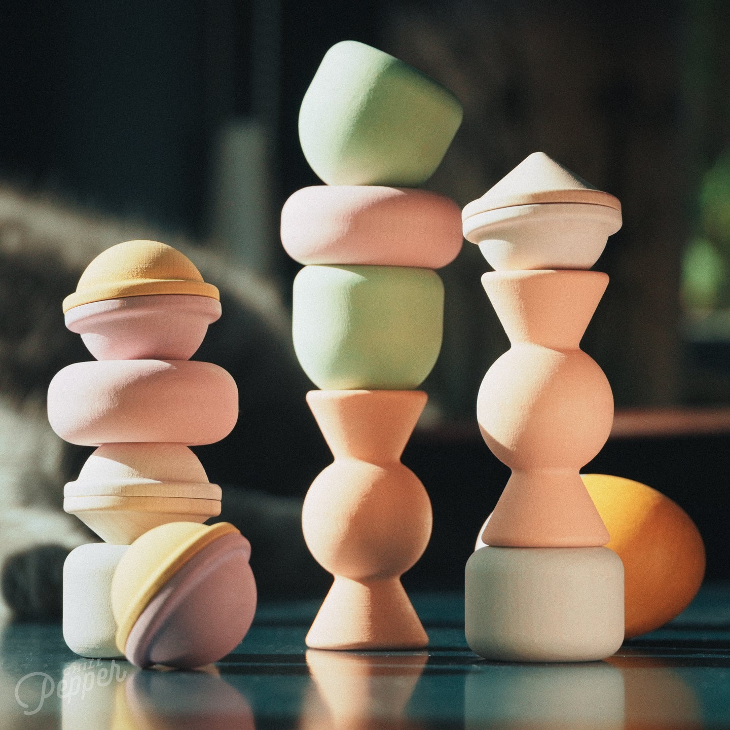 Wooden Chill Pepper Treats stacking and spinning game for ages 3 and up, made from eco-friendly maple wood and non-toxic, water-based paints. The set includes a variety of pastel-colored candy-shaped pieces and a unique Magic Egg for open-ended play. Here you see them stacked in various ways
