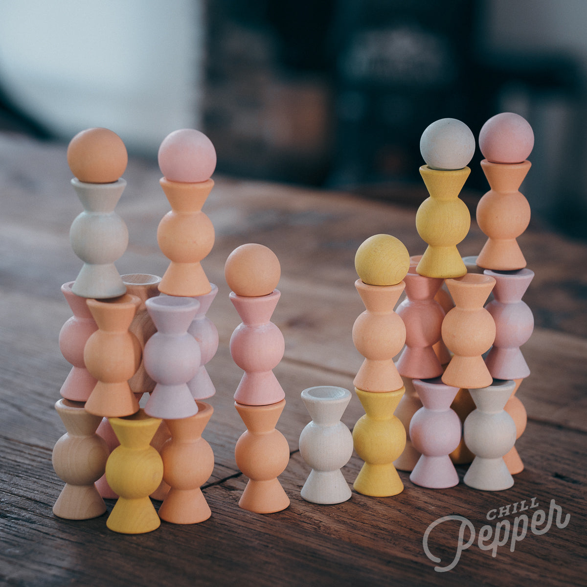 Wooden Chill Pepper Sweets stacking and spinning game for ages 3 and up, made from eco-friendly maple wood and non-toxic, water-based paints. The set includes 27 pastel-colored candy-shaped pieces and 6 gumballs for open-ended play.