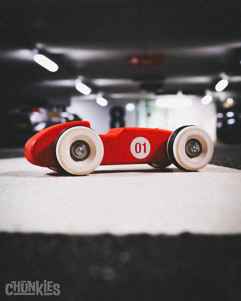 Side view of sleek wooden racing formula 1 car Chunkies No. 01 Single Seat design in an urban parking garage. This cool heavy weight racer is ready for any adventure, big or small. Great collectors item for car lovers too.