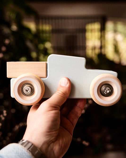 Hand holding large wooden pick-up truck Chunkies No. 02 showing solid quality and scale. Made in europe. Sustainable solid wood. Ready for the next generation. 
