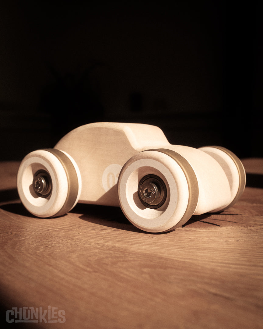 3/4 front view of the curvy Chunkies Bug made by Chill Pepper in Europe. Here on a rustic wooden table as it fits in every interior. The big wheels and skate bearings make for a smooth ride.