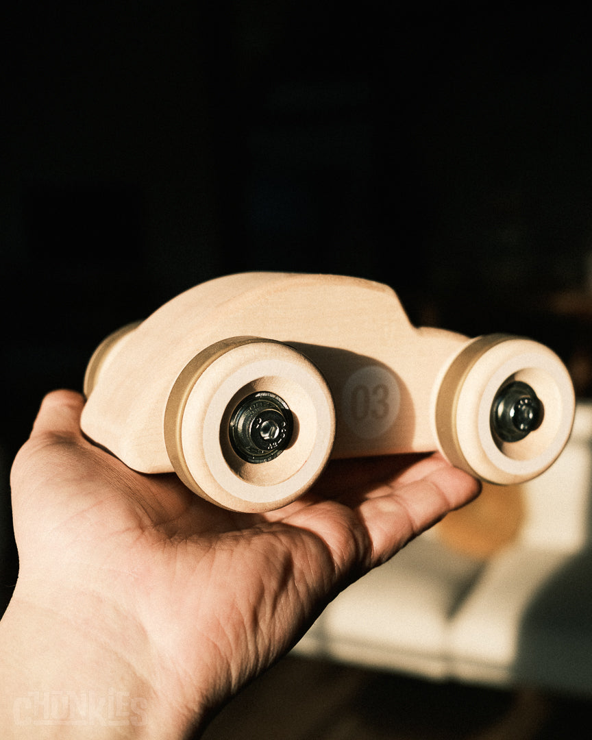 Hand held picture of the Chunkies The Bug natural maple wooden toy car against a dark background. This big little boy will go on many real and imaginative adventures. Probably the most popular toy your child has.