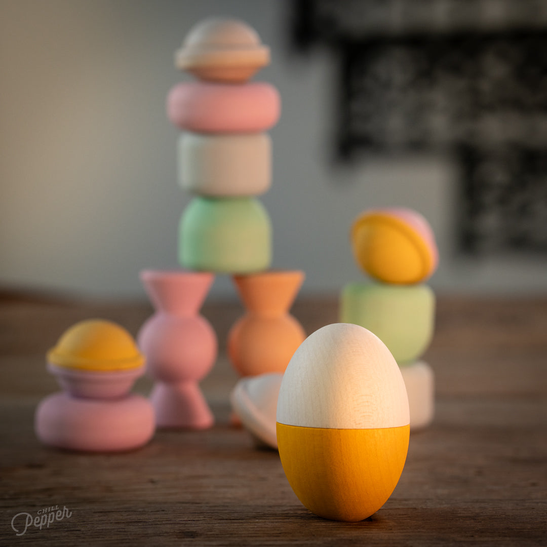 Wooden Chill Pepper Treats stacking and spinning game for ages 3 and up, made from eco-friendly maple wood and non-toxic, water-based paints. The set includes a variety of pastel-colored candy-shaped pieces and a unique Magic Egg for open-ended play.