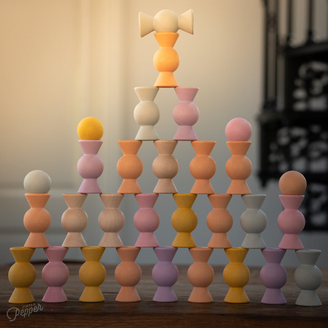 Wooden Chill Pepper Sweets stacking and spinning game for ages 3 and up, made from eco-friendly maple wood and non-toxic, water-based paints. The set includes 27 pastel-colored candy-shaped pieces and 6 gumballs for open-ended play.