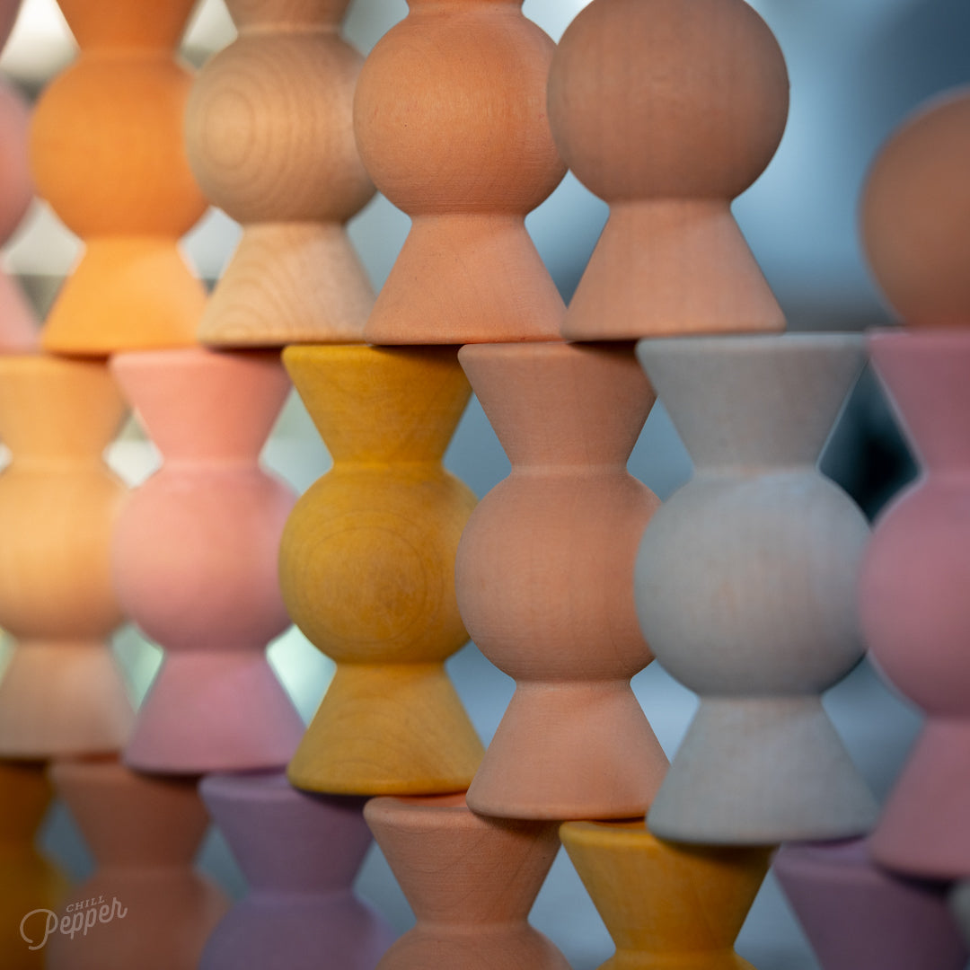 Wooden Chill Pepper Sweets stacking and spinning game for ages 3 and up, made from eco-friendly maple wood and non-toxic, water-based paints. The set includes 27 pastel-colored candy-shaped pieces and 6 gumballs for open-ended play.
